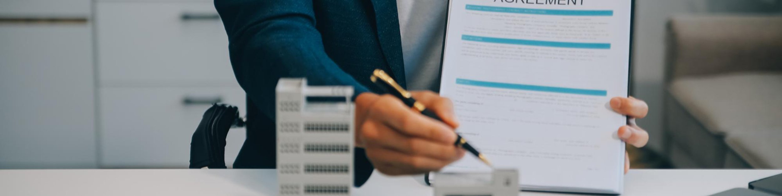 a real estate lawyer holds a contract in from of a model office